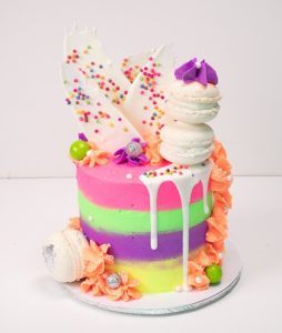 Oh My Cake's Rainbow highlights cake, which is a cake with neon rainbow coloured buttercream icing and contrasting white chocolate shard and macaroon toppings